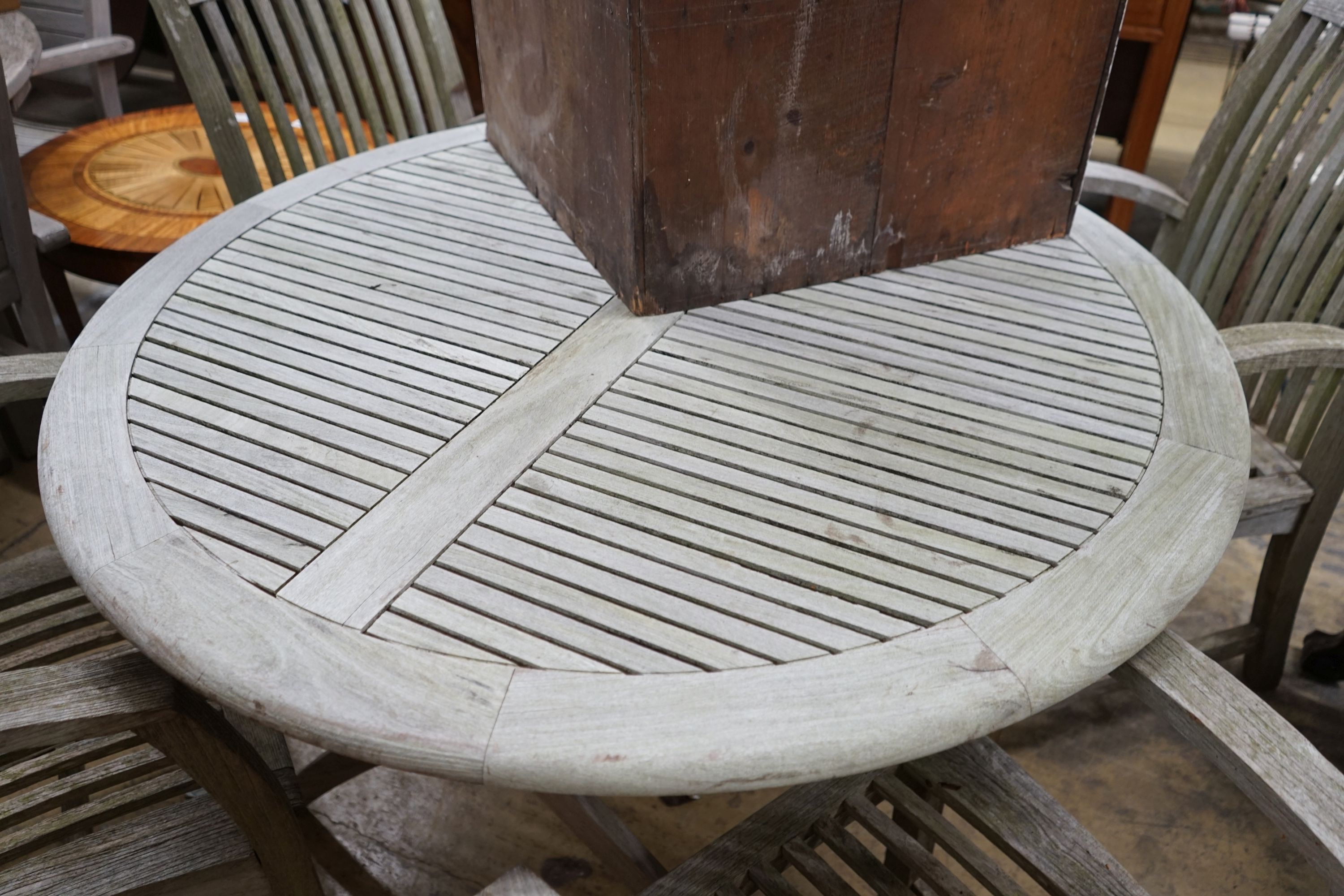 A circular weathered teak folding garden table, diameter 120cm, height 74cm and four teak chairs